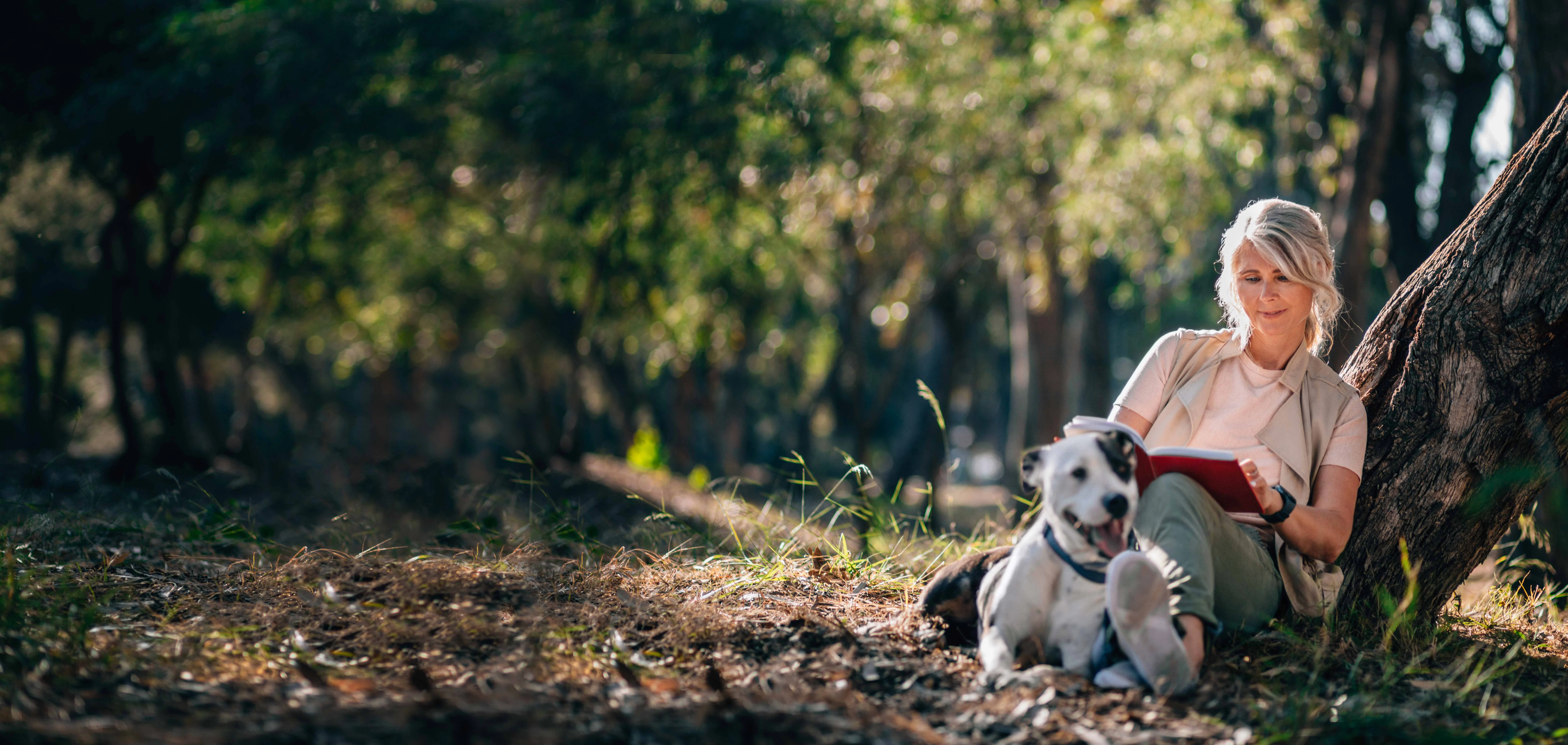 a person sitting in the woods with a dog