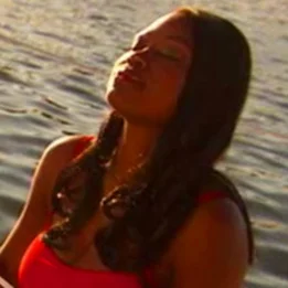 a person with a red shirt and a red shirt with a body of water behind the