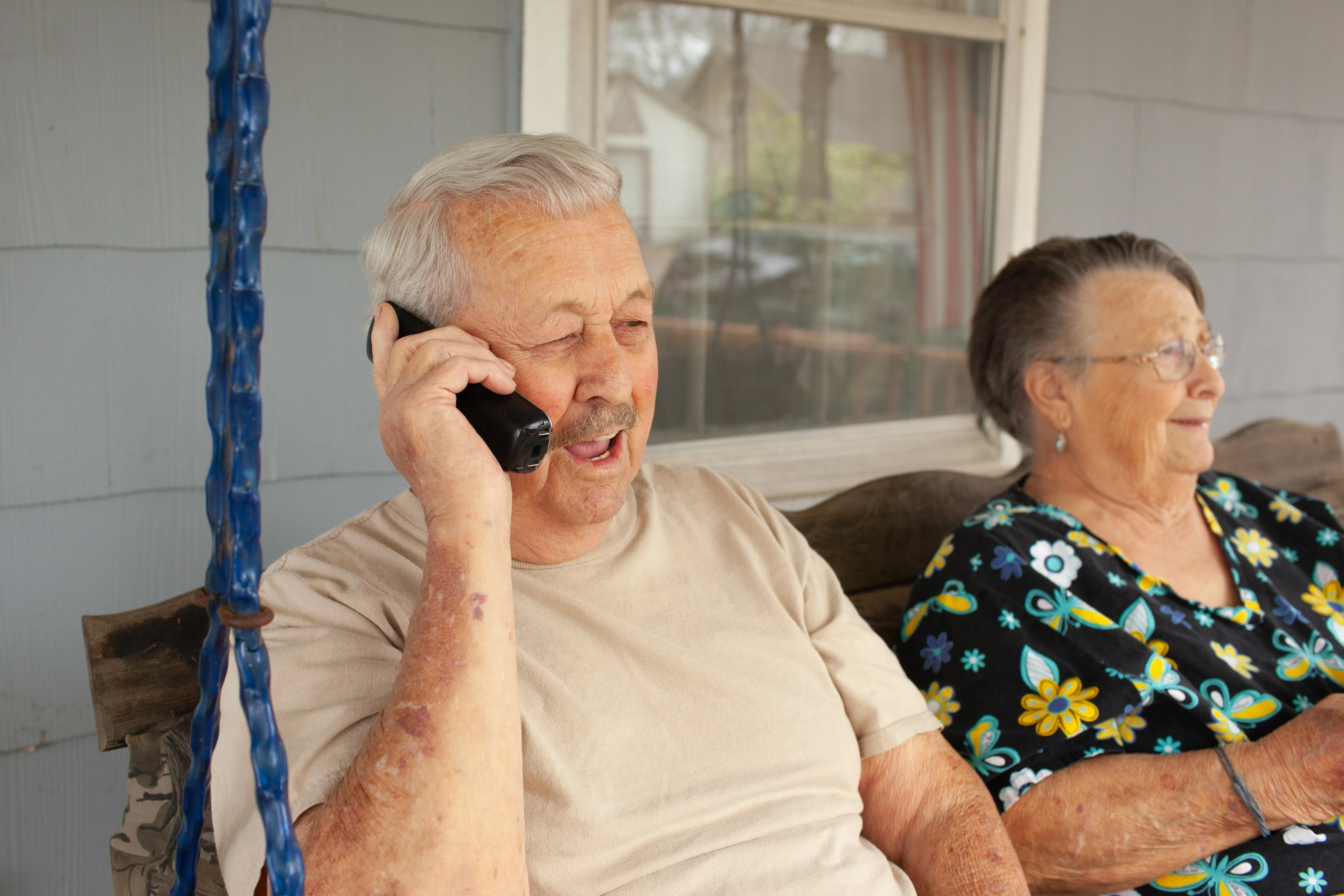年配の男性の隣で携帯電話で話している老人