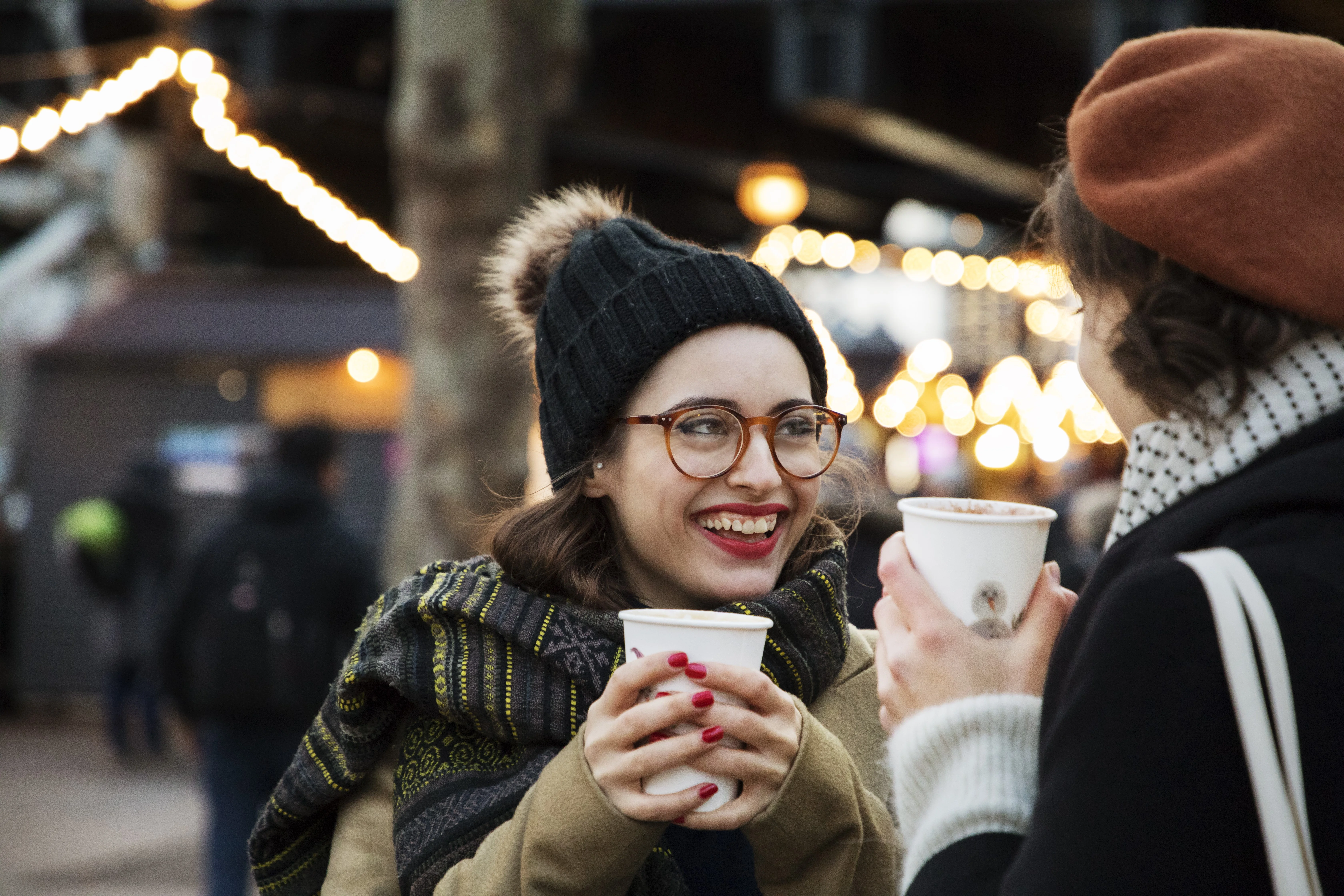 en person, der holder en kop og en mobiltelefon