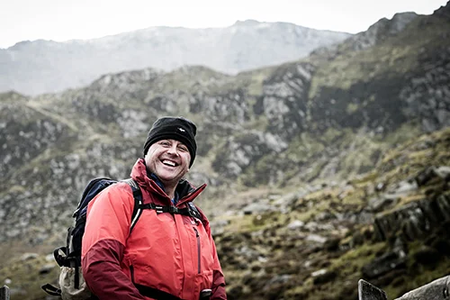 a person smiling with mountains in the background